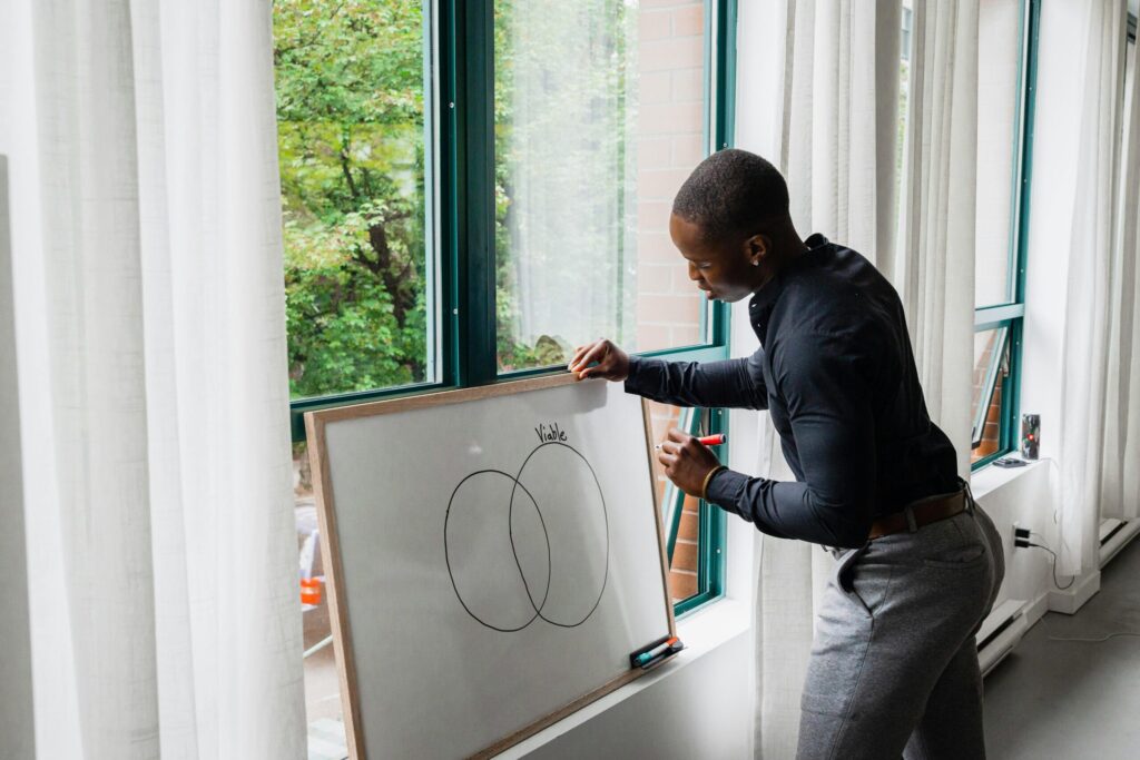 Business professional drawing a Venn diagram on a whiteboard at home.